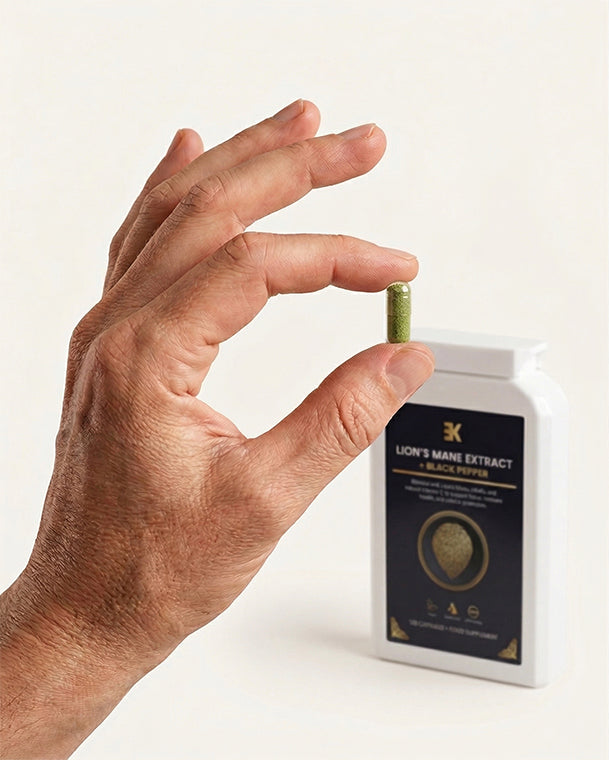 Hand holding a supplement capsule with a bottle labeled 'Lion's Mane Extract' on a white background