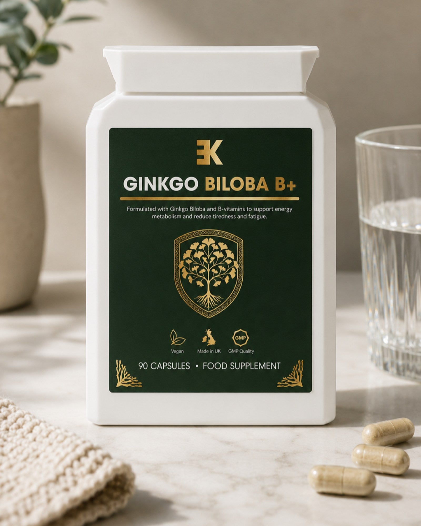 Supplement bottle labeled 'Ginkgo Biloba B+' on a table with capsules and a glass of water.